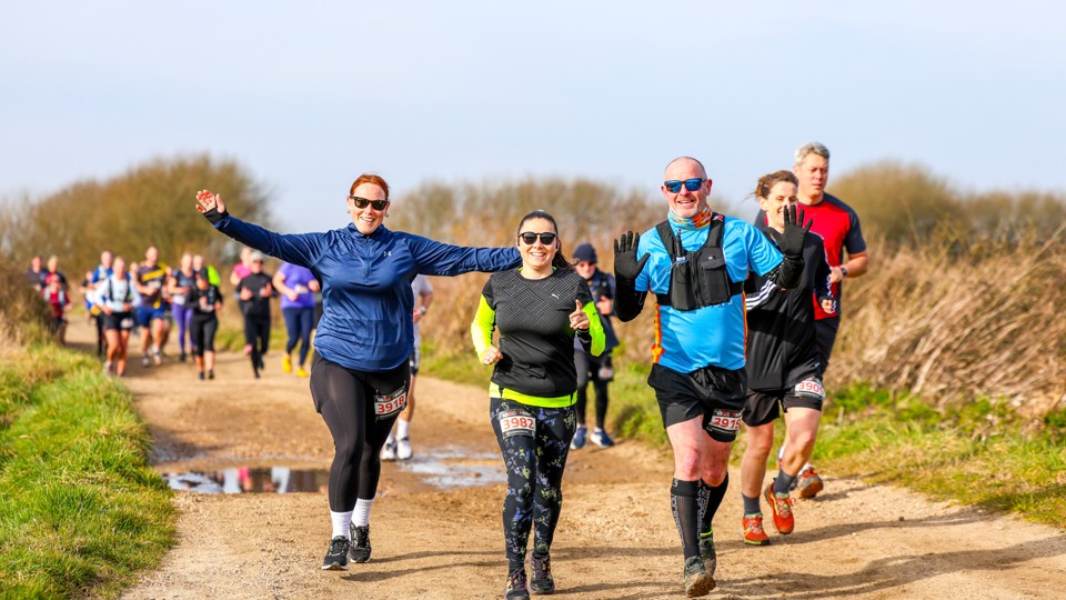 Group of runners smiling and waving during a race